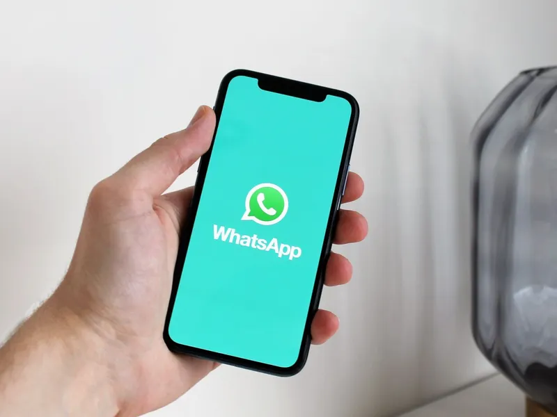 Mão segurando o celular com o WhatsApp aberto
